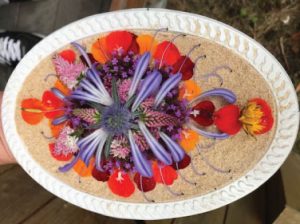 An oval platter with purple, pink, range and yellow flower petals arranged in a delicate pattern.